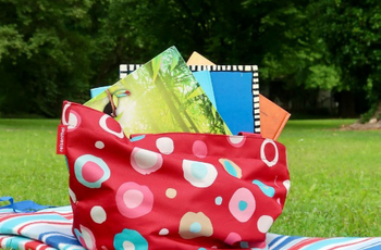 Picknickdecke mit Büchertasche auf Wiese