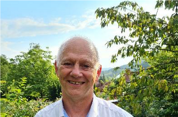 Foto eines lächelnden älteren Mannes mit weißem Hemd
