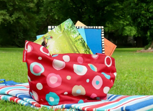 Picknickdecke mit Büchertasche auf Wiese