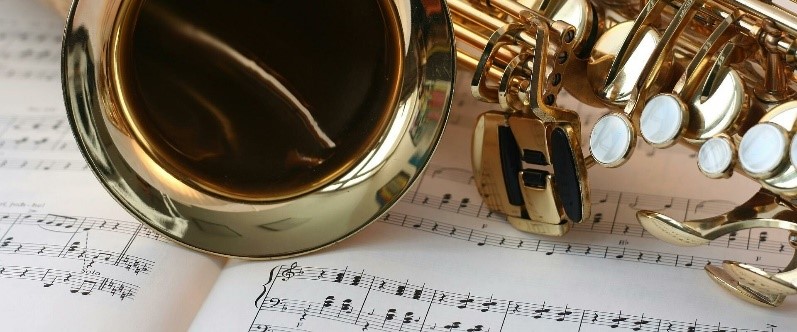Foto eines Saxophon, das auf Notenblättern liegt