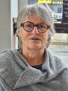 Foto einer Frau mit kurzen Gaaren, Brille und grauem Pullover