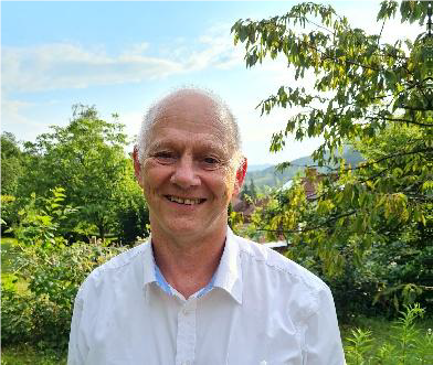 Foto eines lächelnden älteren Mannes mit weißem Hemd