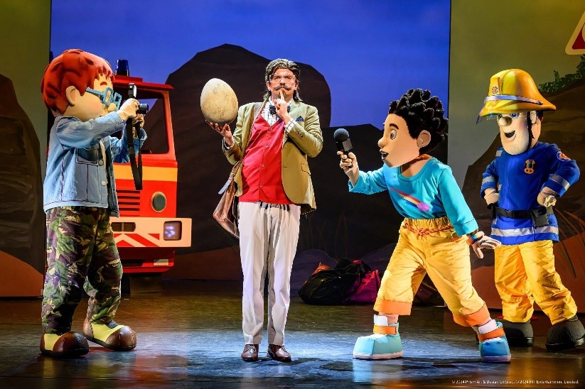 Foto einer Szene aus dem Theaterstück: die Hauptdarsteller und ein Feuerwehrauto